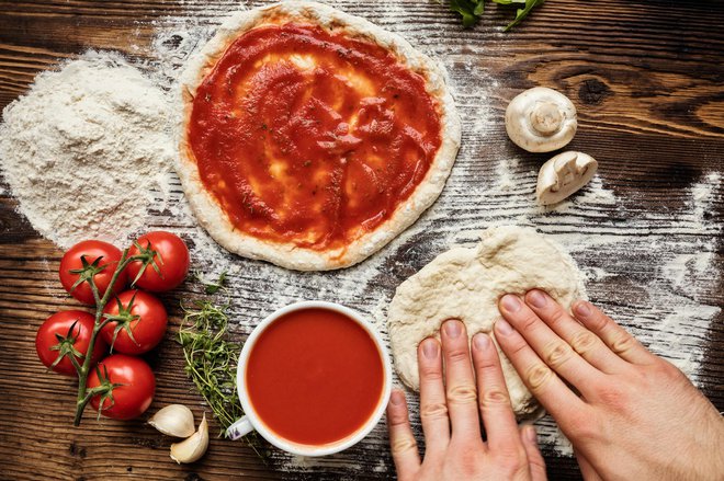 Fresh original Italian raw pizza preparation, close-up of man hands in action
