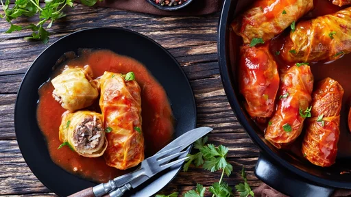cabbage rolls stuffed with ground beef and rice, cooked to perfection with a tangy tomato sauce in a dutch oven and served on a plate with cutlery, view from above, close-up, flatlay (cabbage rolls stuffed with ground beef and rice, cooked to perfecti
