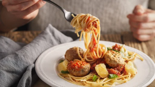 Woman eating spaghetti with meatballs and cheese horizontal