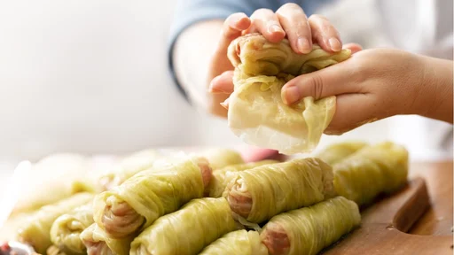 Skillful hands of women twist cabbage rolls stuffed with minced meat and rice