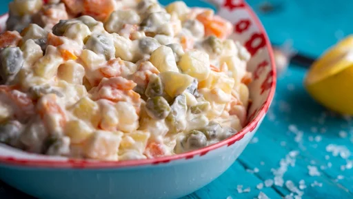 Bowl of traditional russian salad on blue wooden table.