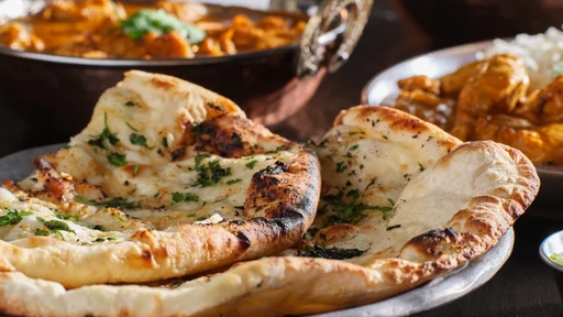 indian naan bread with herbs and garlic seasoning on plate