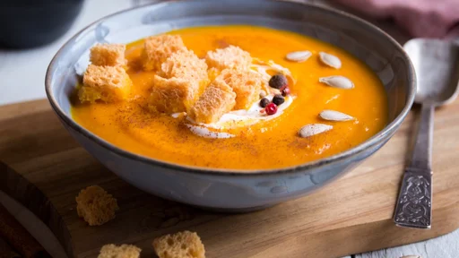 pumpkin soup with croutons on white wooden background