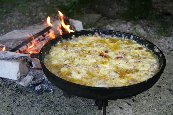 Priprava frike v litoželezni posodi nad ognjem.