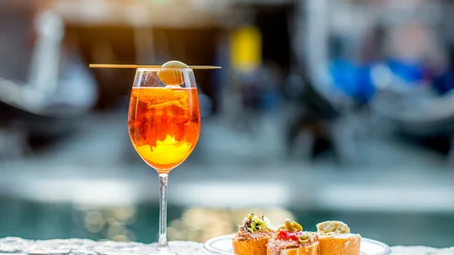 Spritz Aperol drink with venetian traditional snacks cicchetti on the water chanal background in Venice. Traditioanal italian aperitif. Image with small depth of field