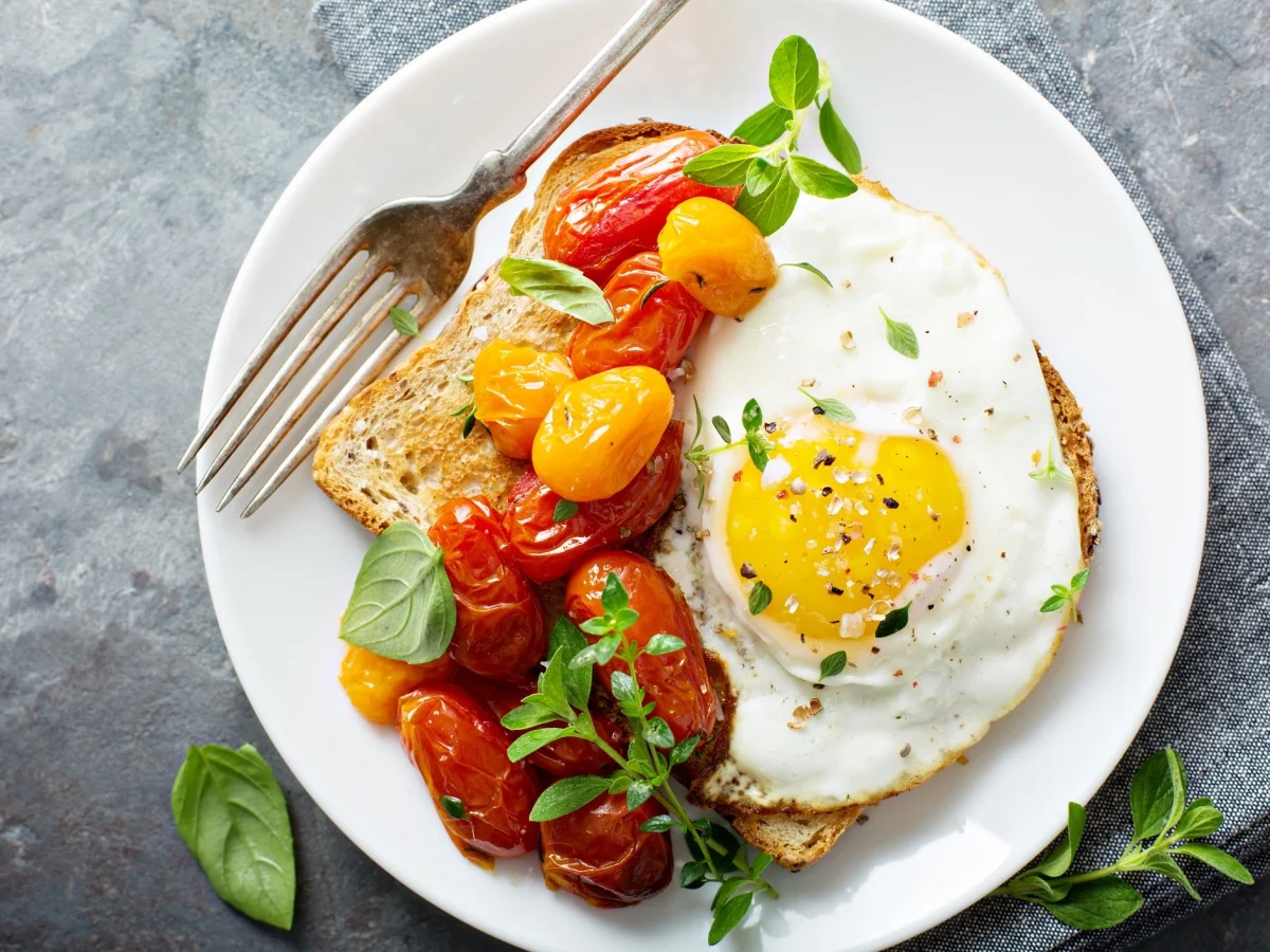 Multigrain toast with fried egg, fresh herbs and roasted tomatoes