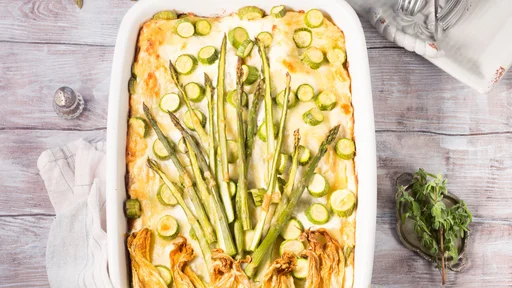 Home made asparagus lasagna casserole with zucchini, ricotta, mozzarella cheese and marjoram herb in a ceramic tin on wooden table. Rustic spring baked one plate food (Home made asparagus lasagna casserole with zucchini, ricotta, mozzarella cheese and