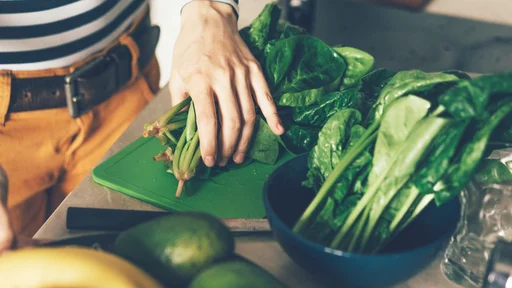 The process of preparing food for cooking dinner. Sliced spinach. Female hands. Kitchen care.
