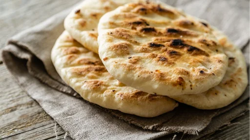 Traditional pita bread on rustic wood background, copy space