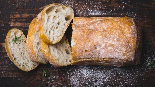 Italian ciabatta bread cut in slices on dark wooden background