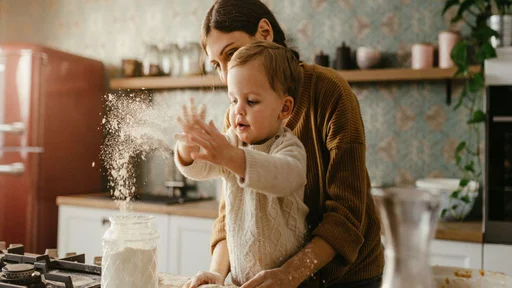 Mother and son are preparing dough for cookies together in the morning. Kid is throwing flour and is happy.