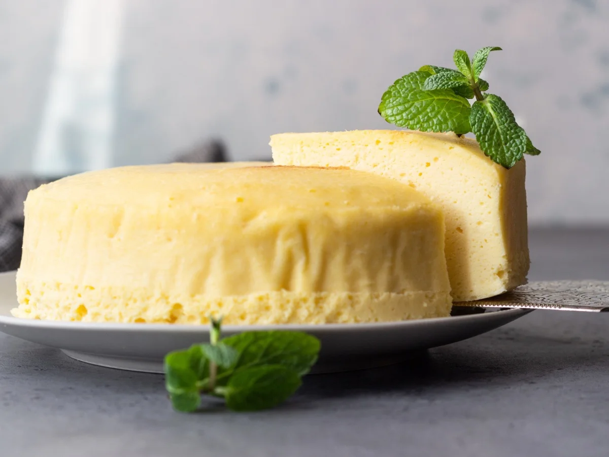 Japanese cotton cheesecake with mint on a grey plate. No crust cheesecake. Grey stone or concrete background. Selective focus, copy space.