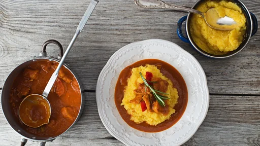 Goulash with polenta on wooden background close up