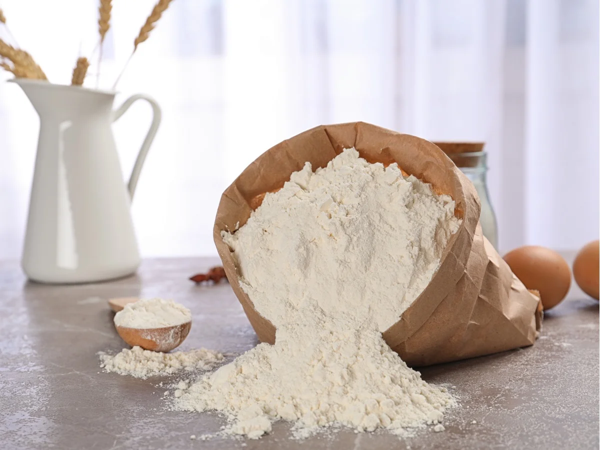 Paper bag and spoon with flour on table