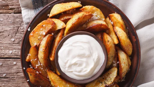 Tasty potato wedges with herbs and mayonnaise on a plate closeup on the table. horizontal view from above