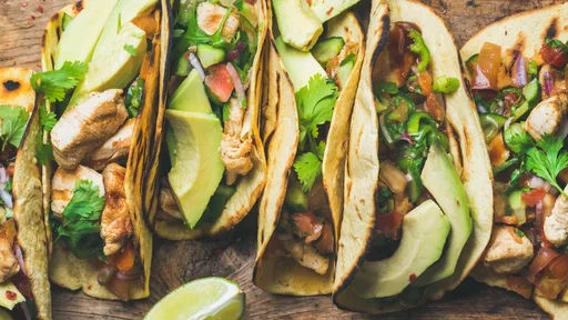 Tacos with grilled chicken, avocado, fresh salsa sauce and limes over rustic wooden background, top view. Healthy low carb and low fat lunch or food for company. Dieting and weight loss concept (Tacos with grilled chicken, avocado, fresh salsa sauce a