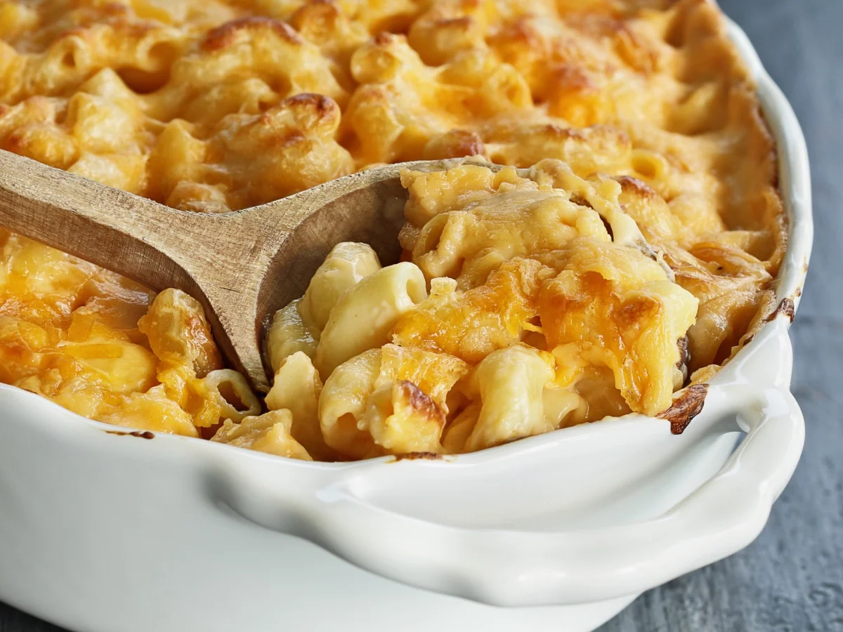 High angel view of a dish of fresh baked macaroni and cheese with a wooden spoon over a rustic dark background. (High angel view of a dish of fresh baked macaroni and cheese with a wooden spoon over a rustic dark background., ASCII, 112 components, 11