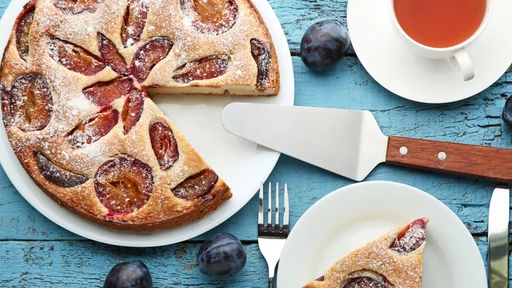 Sweet plum cake with cup of tea on blue wooden table