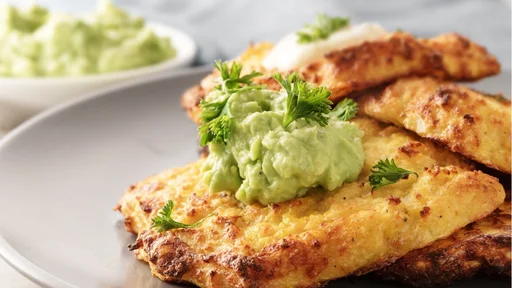 golden crisp rosti from cauliflowerand parmesan cheese with avocado dips and parsley garnish on a gray plate, close-up, selective focus, narrow depth of field (golden crisp rosti from cauliflowerand parmesan cheese with avocado dips and parsley garnis