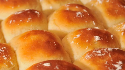 Fresh baked dinner rolls, just out of the oven. Golden brown with a light cheese garnish.