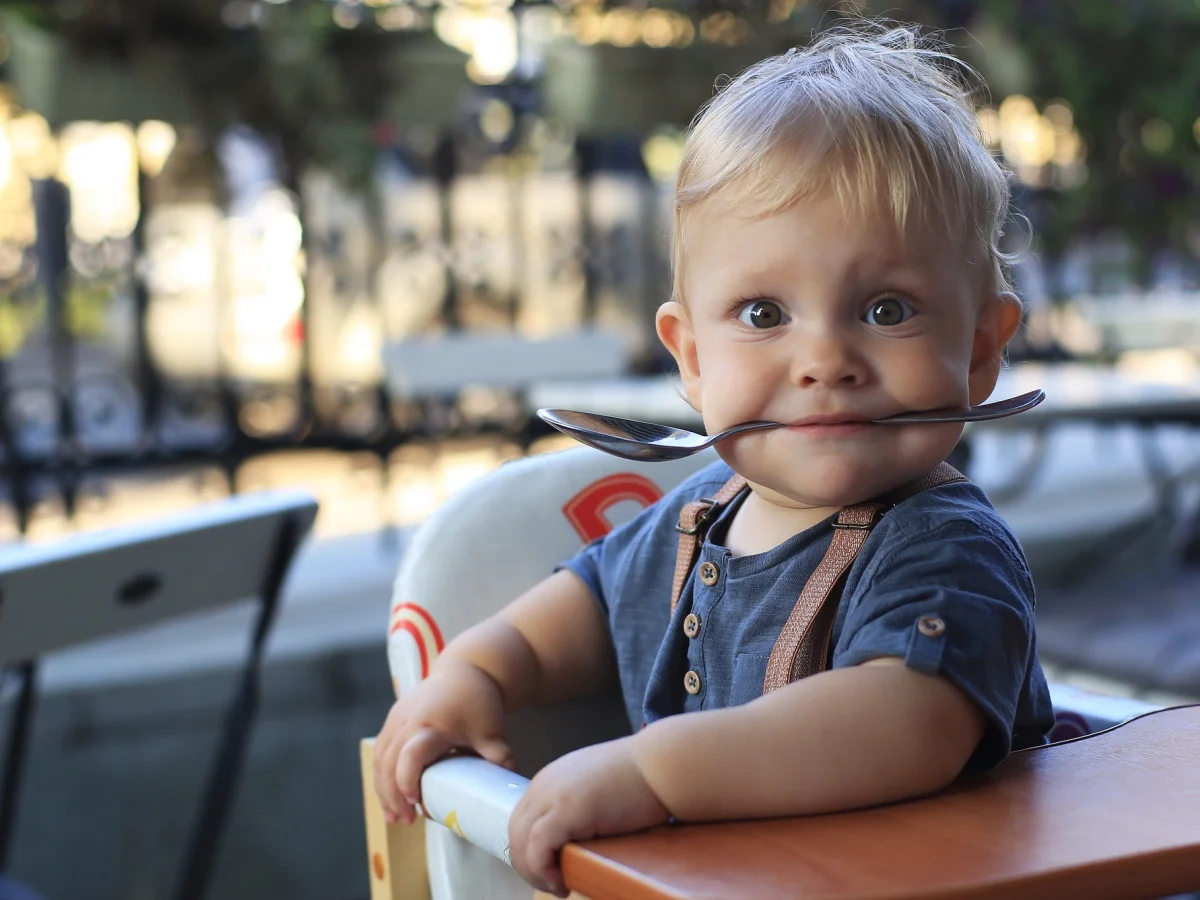 Little boy is sitting in a cafe with a spoon