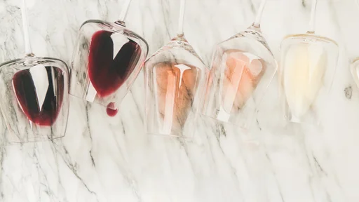 Flat-lay of red, rose and white wine in glasses and corkscrews over grey marble background, top view, copy space. Bojole nouveau, wine bar, winery, wine degustation concept (Flat-lay of red, rose and white wine in glasses and corkscrews over grey marb