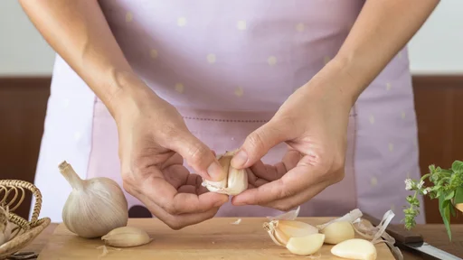 Woman peeling garlic preparation for cooking in the kitchen.