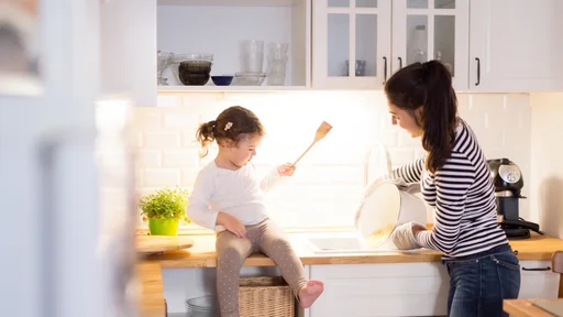 Beautiful young mother with her cute little daughter in the kitchen, cooking pasta together