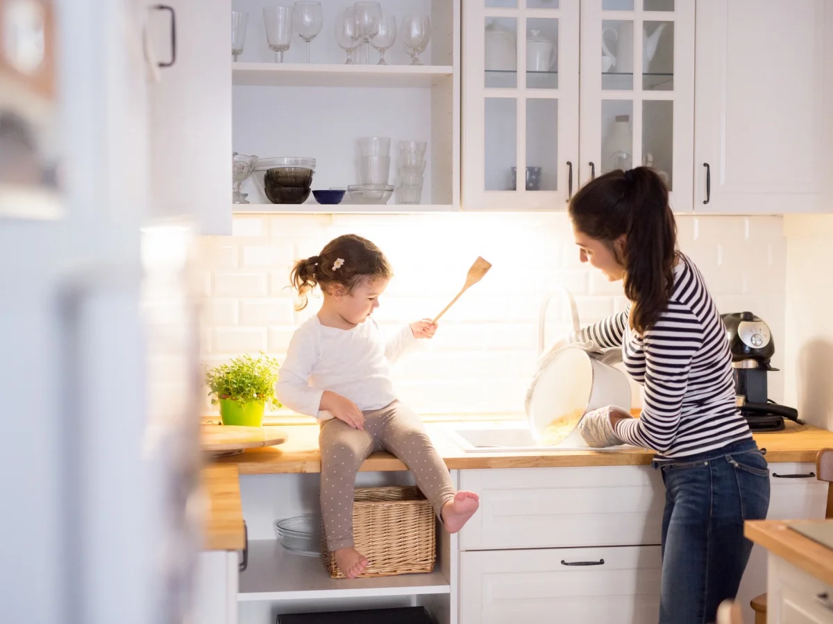 Beautiful young mother with her cute little daughter in the kitchen, cooking pasta together