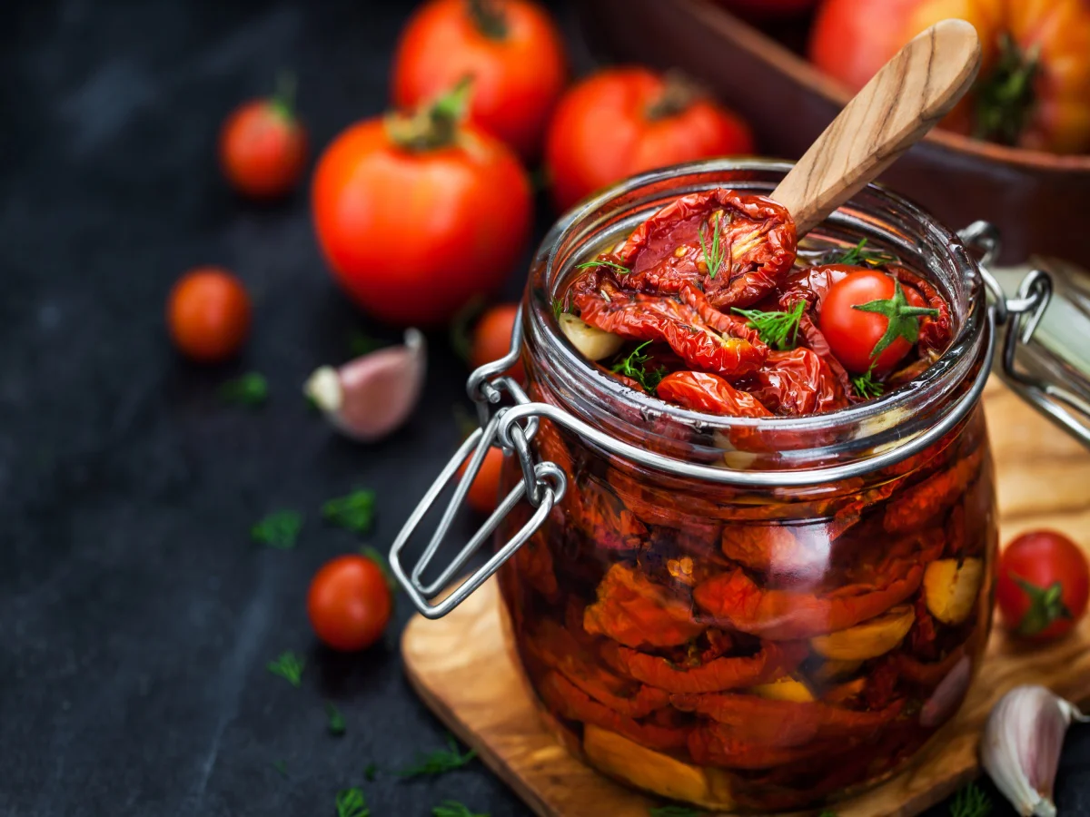 Sun dried tomatoes with garlic and olive oil in a jar on dark background