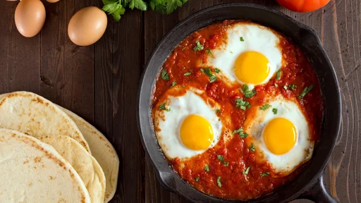 Shakshuka with eggs, tomato, and parsley in a cast iron pan.