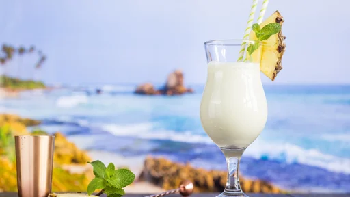Cold pina colada cocktail in a glass on the beach with seascape background
