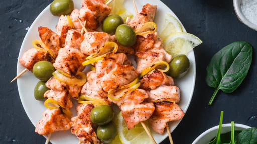 Salmon skewers, olives, spinach - snack, appetizers, tapas. Grilled salmon fish skewer on a dark background, top view