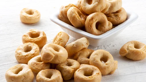 Italian taralli crackers for a delicious finger snack served in a small bowl spilling in a pile onto a white wooden board