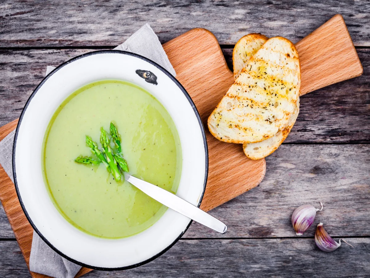 homemade cream soup with asparagus and toasted ciabatta on rustic background