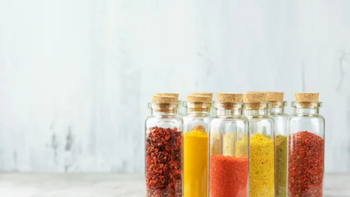 Assorted ground spices in bottles on rustic wood.
