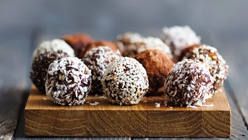 Healthy raw energy bites with cocoa, coconut, sesame, chia. Vegan truffles on a grey background. Copy space for text. Vertical