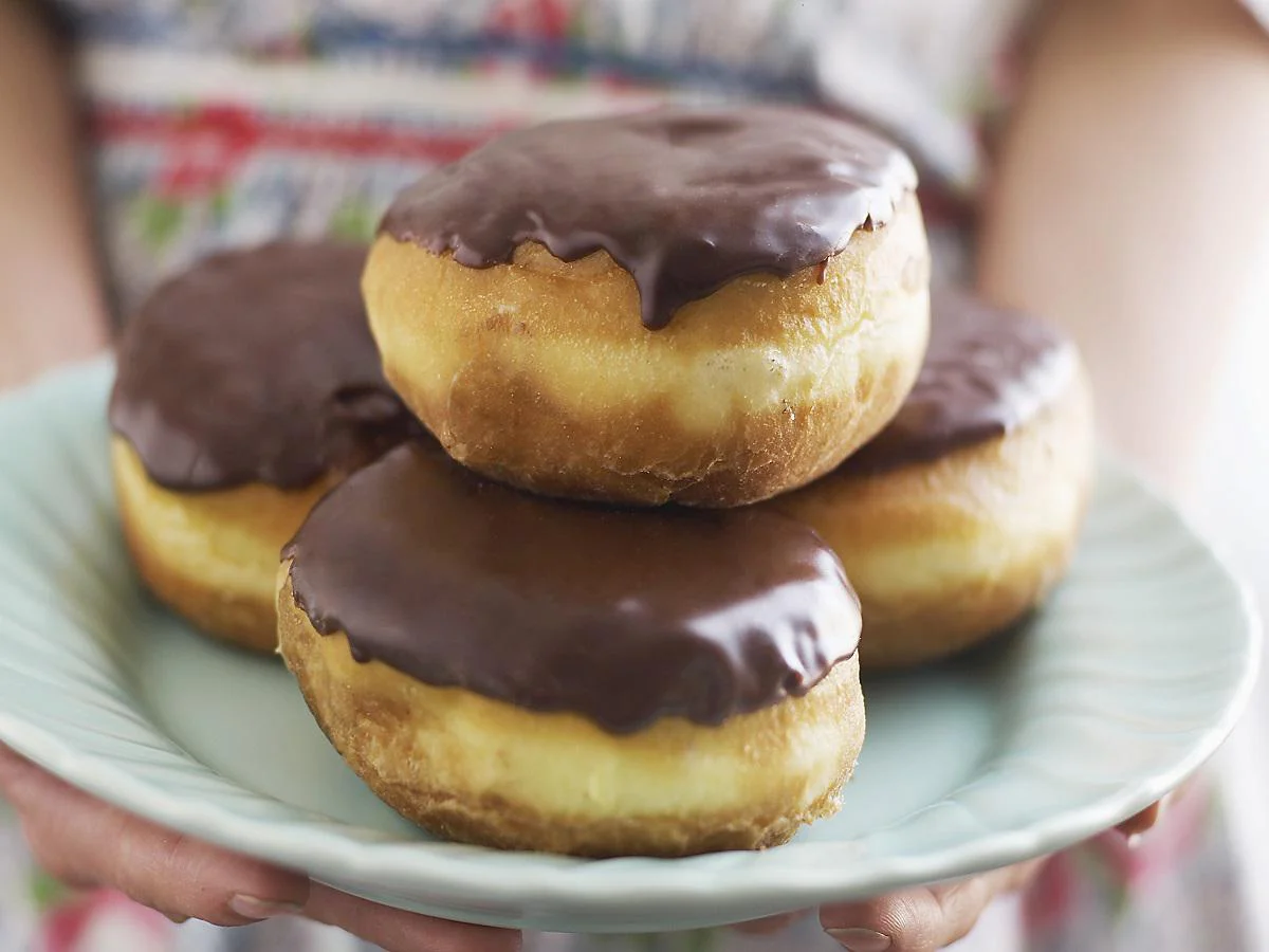 Woman holding plate of Boston creme doughnuts