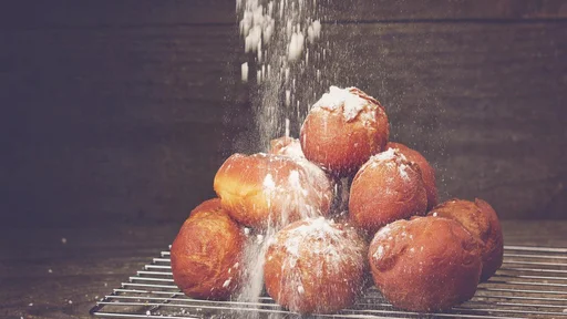 Delicious freshly baked donuts sprinkled with powdered sugar cooling on a wire rack in the kitchen.
