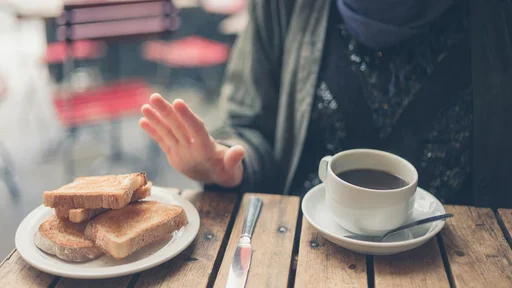 A young woman on gluten free diet is saying no thanks to bread in a cafe