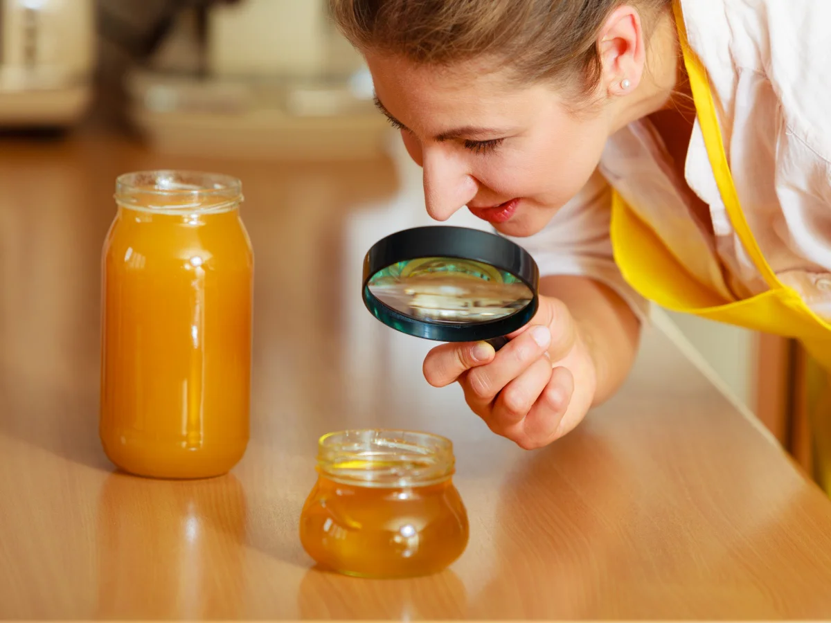 Mature woman female inspecting testing honey food with magnifying glass.