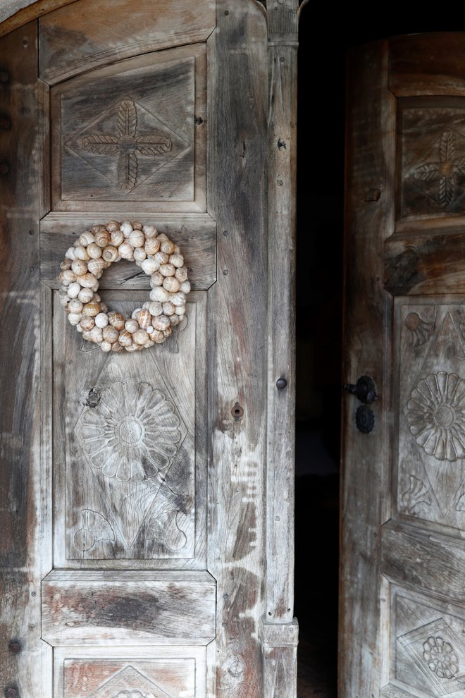 Na vhodnih vratih obiskovalca pričaka venček, narejen iz polžjih hišk, izvrstna kombinacija s starimi rezbarjenimi kmečkimi vrati. Foto: Uroš Hočevar/Delo