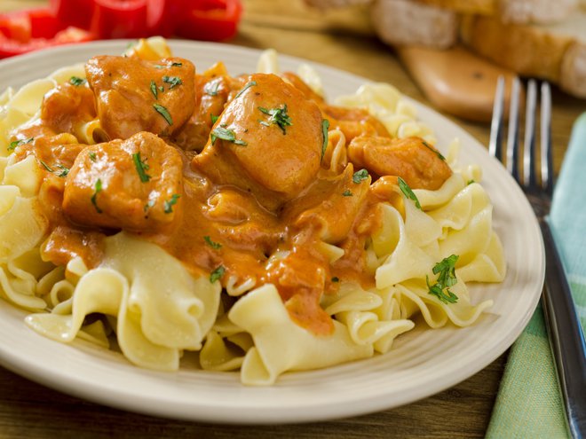 A plate of delicious, creamy, chicken paprikash with egg noodles and red pepper.