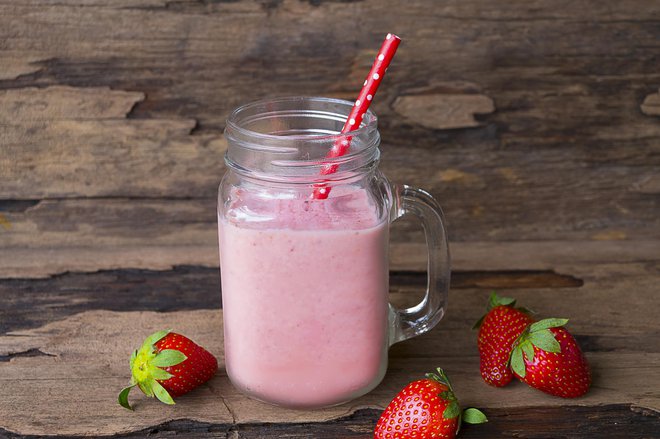 Strawberry smoothies colorful fruit juice milkshake blend beverage healthy high protein the taste yummy In glass drink episode morning on wood background.