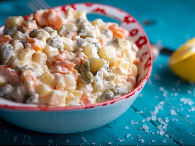 Bowl of traditional russian salad on blue wooden table.