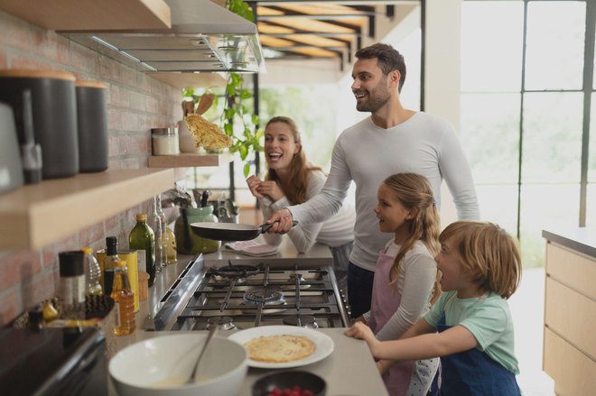 Front view of happy Caucasian family preparing food in kitchen in a comfortable home