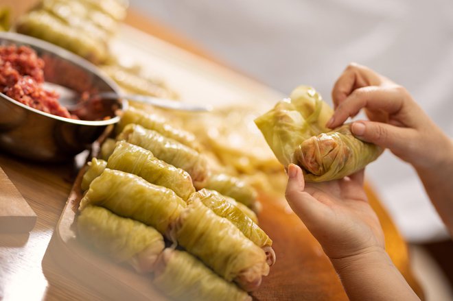 Chef prepares stuffed cabbage rolls on a cutting board close-up