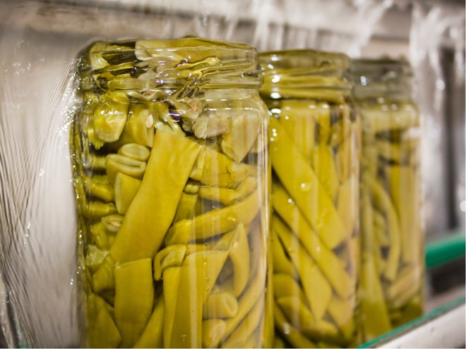 Filling green beans jars with sterilized water before putting the lids on.