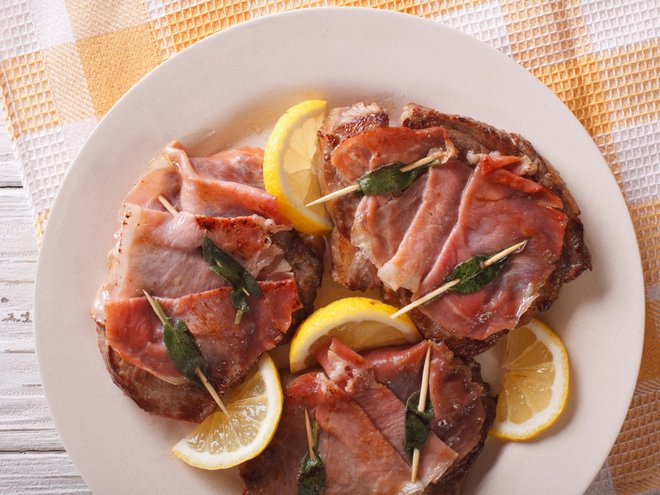 Italian cuisine: beef saltimbocca with lemon close up on a plate. Horizontal view from above