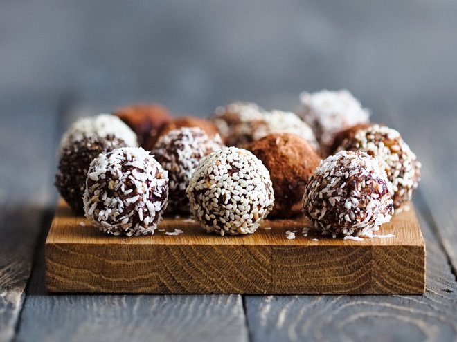 Healthy raw energy bites with cocoa, coconut, sesame, chia. Vegan truffles on a grey background. Copy space for text. Vertical